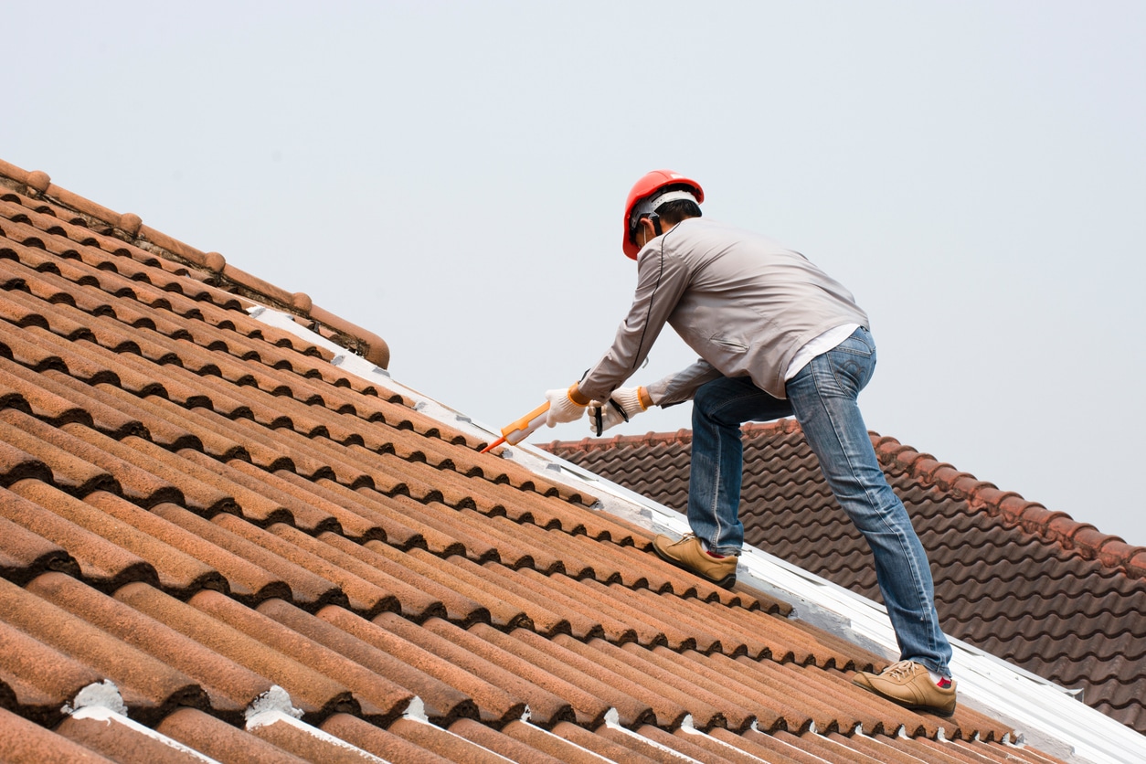 Caulk gun Technician man hand using glue gun with silicone adhesive or manual caulking gun with polyurethane to seal the leakage on the roof. Installing and building construction concept.
